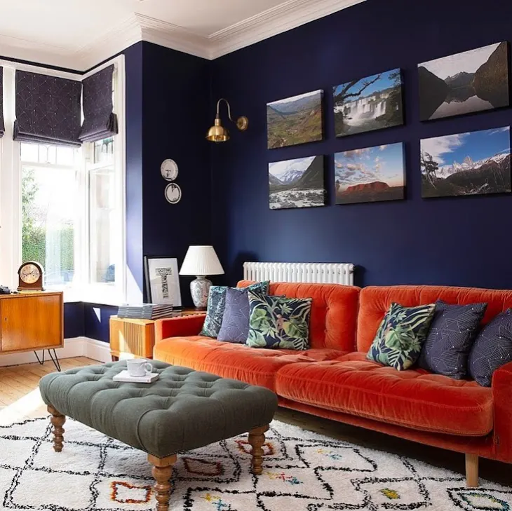 A living room with dark accent wall against orange couch