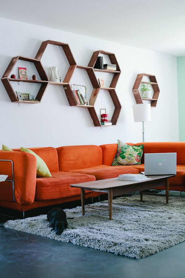 A living room with floating shelves and orange couch 