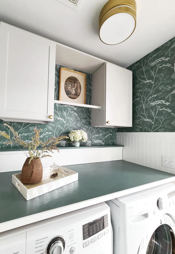 A laundry room with green-patterned wallpaper 