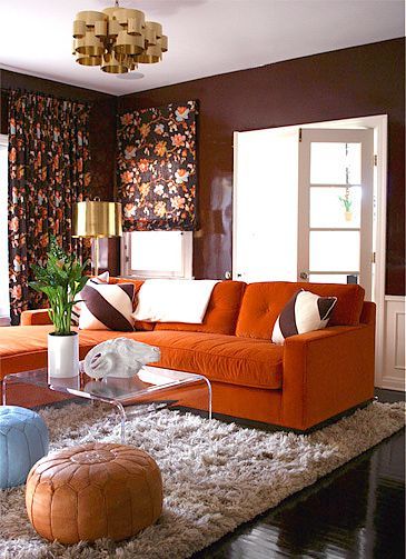 A living room with layered rugs and orange couch 