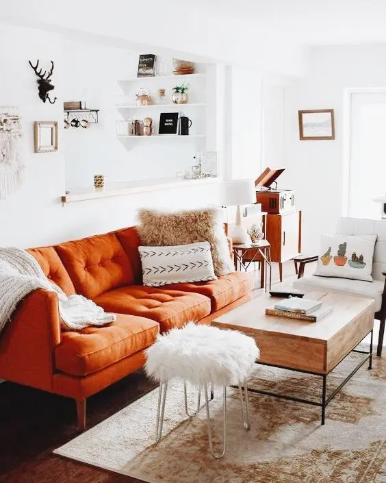 A living room with orange couch and personal accessories 