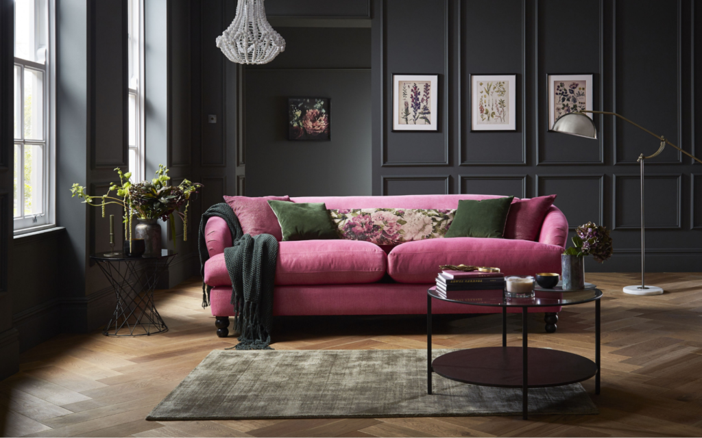 A living room with pink velvet sofa against black wall 