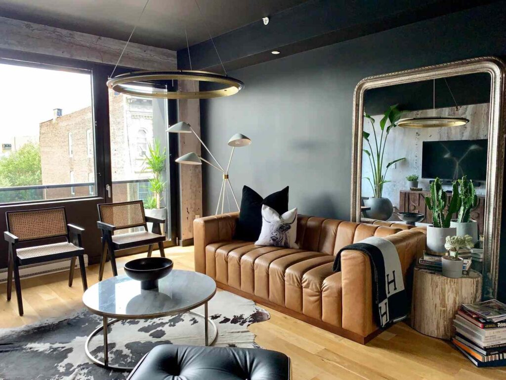 A living room with dark furnitures and mirror 