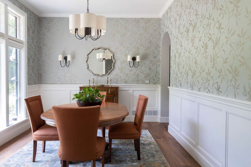 A dining room with molding and wallpaper