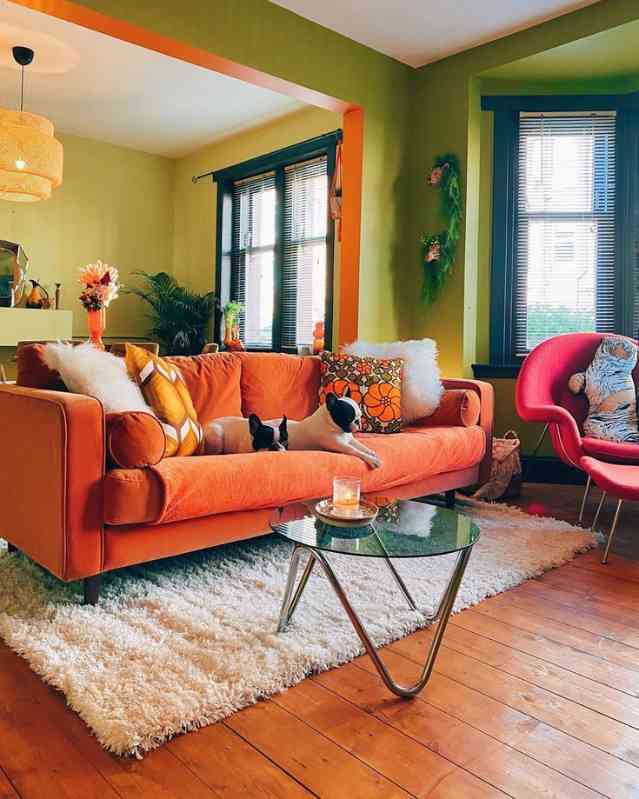 Burnt orange sofa against sage green walls paired with white rug