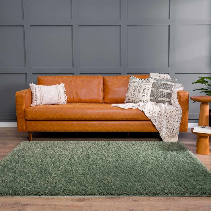 Sage green rug and leather sofa with a grey grid wall