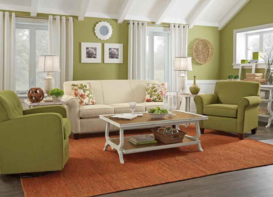 Sage green arm chair with burnt orange rug and cream on sofa and walls