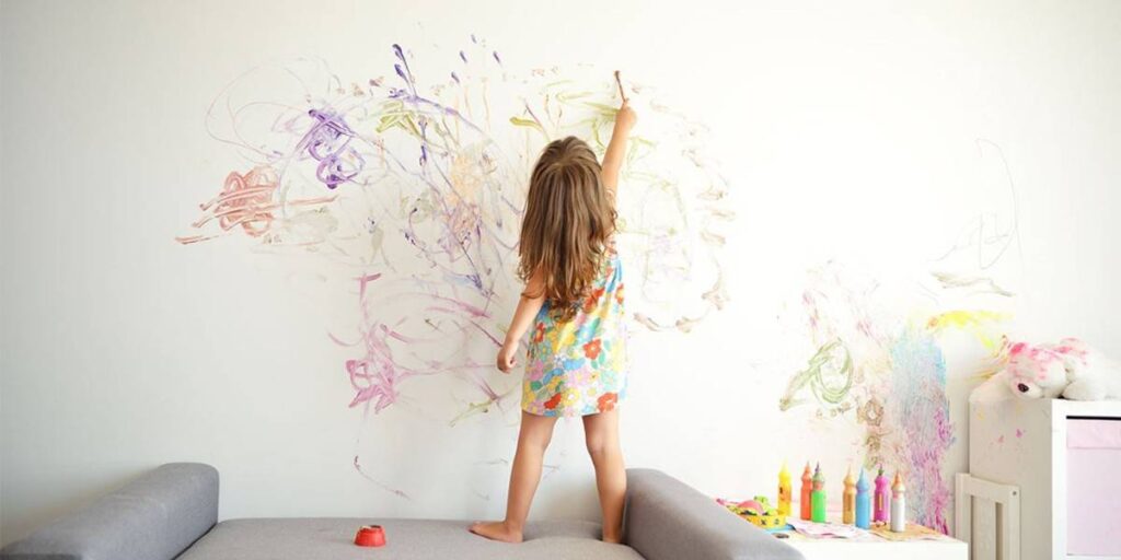 A girl doodling on wall with crayon