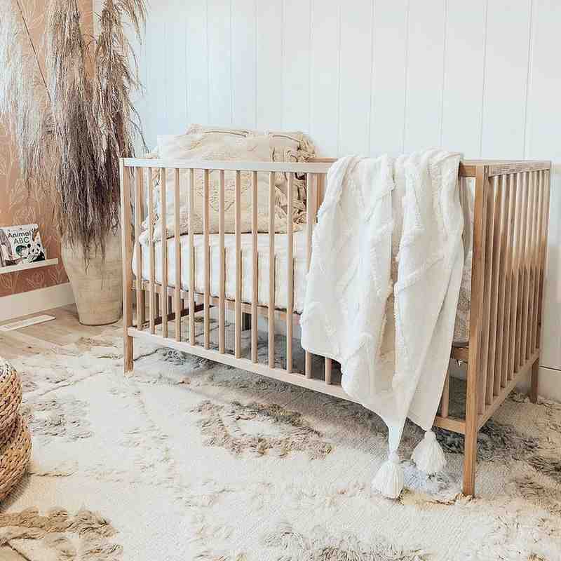 A white and beige rug laying under the babies crib