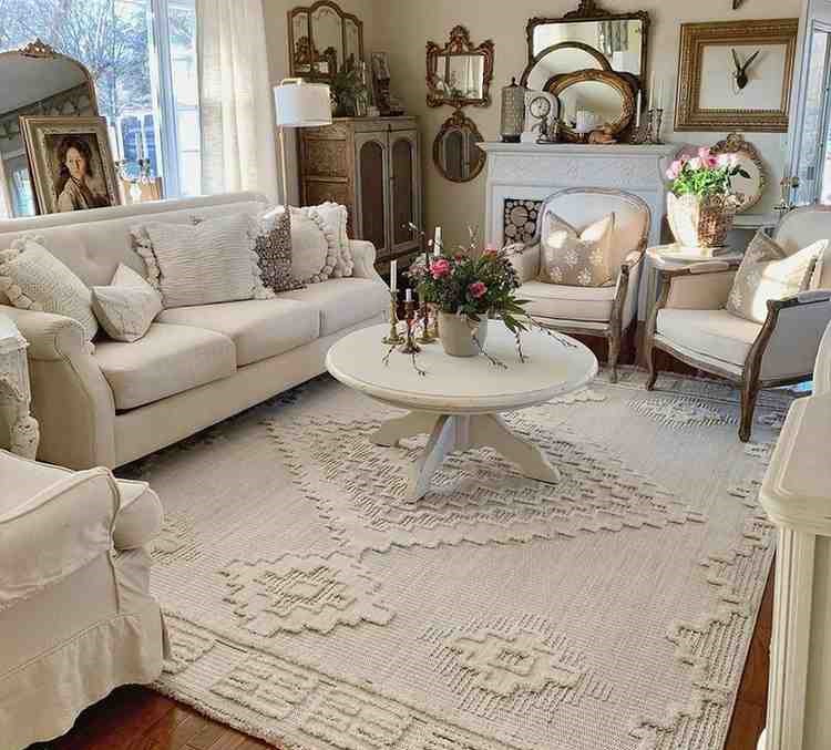 Boho style beige rug and cream sofa set with a coffee center table and a fireplace with mirror placed on it