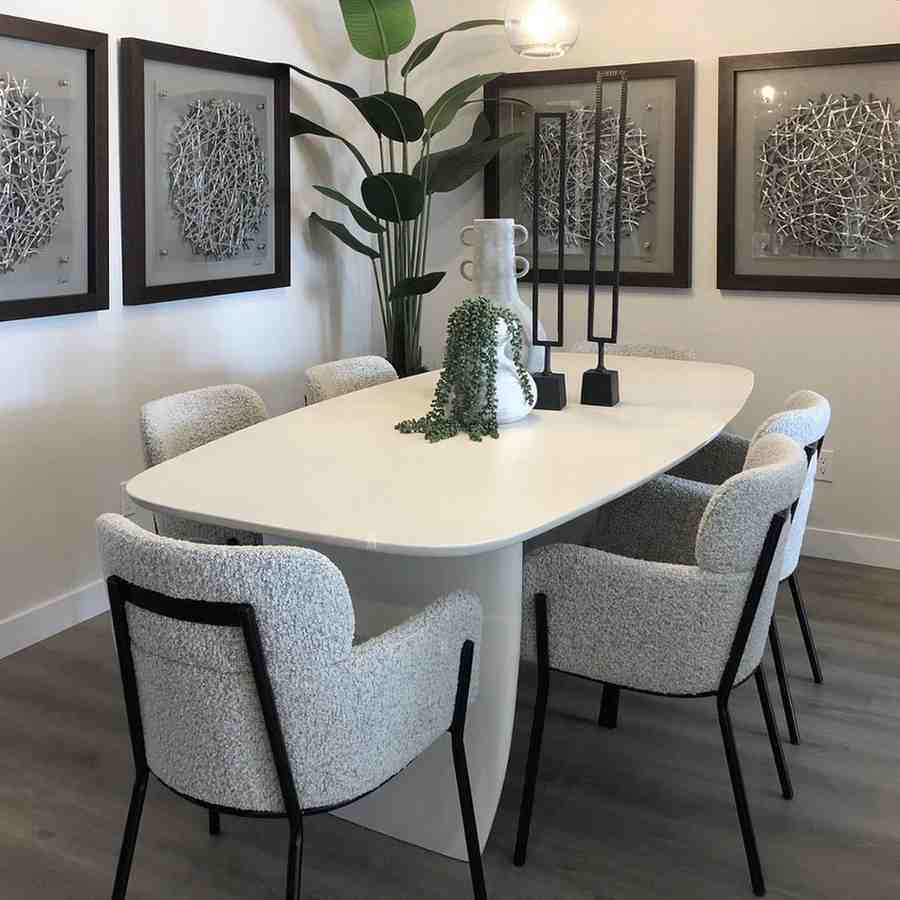Grey color boucle fabric chair and a white dining table with a flower pot placed on it