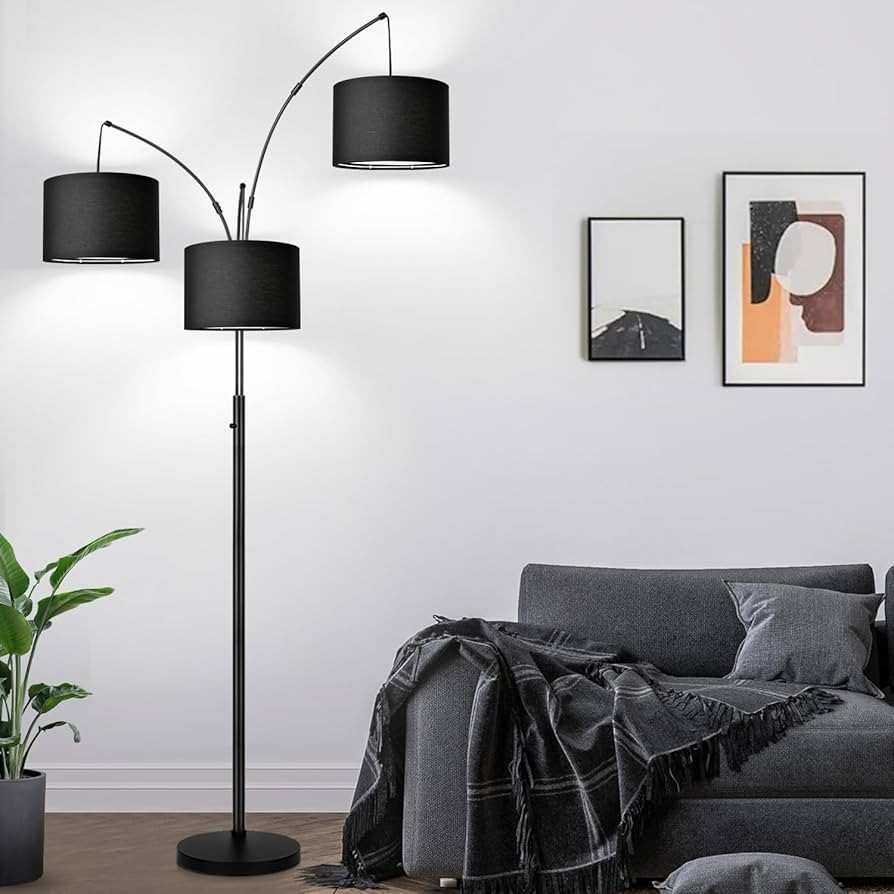 Dark gray floor lamp and a sofa against the white wall and art frames hanged above the sofa