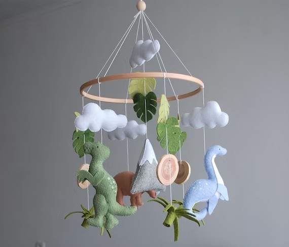 A wooden mobile frame and shaped of cloud and dinosaur hanging on it