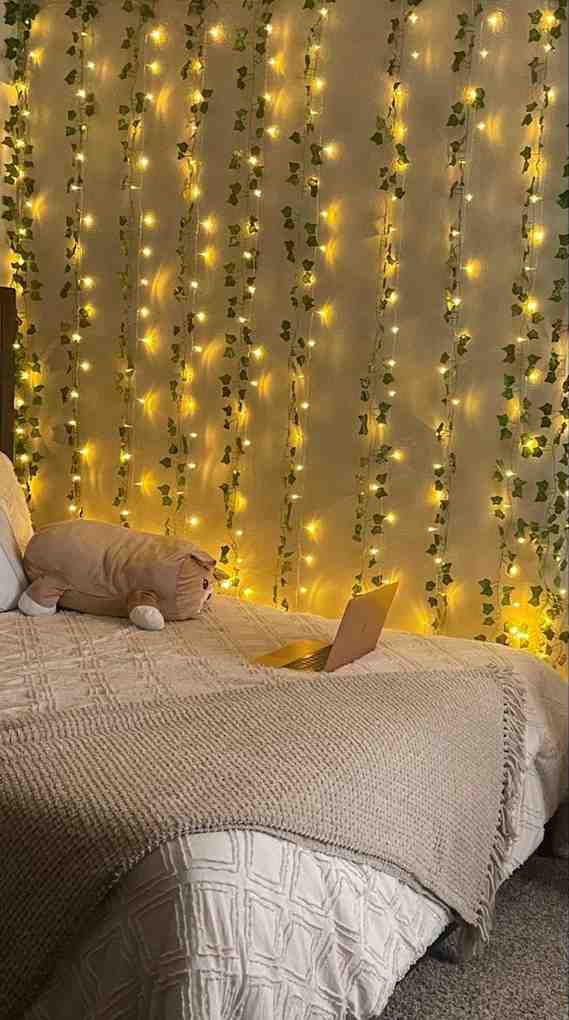 Fairy lights weave into fake plants on white wall for the baddie room