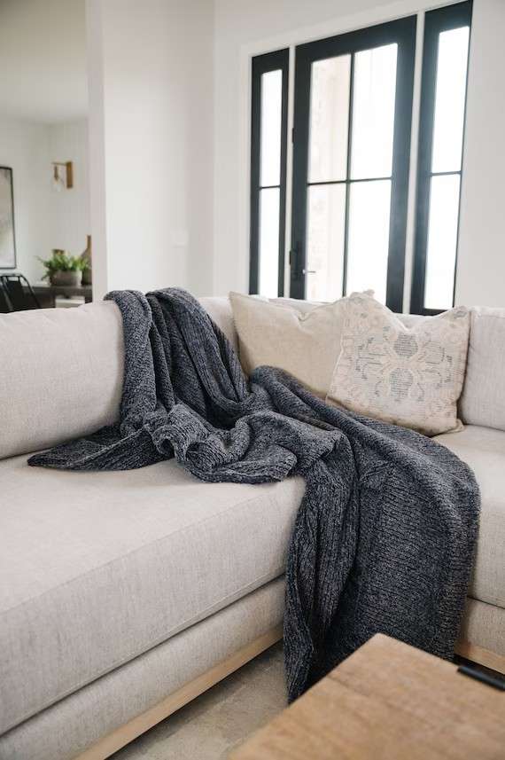 Dark gray throw rug placed on cream sofa in the living room