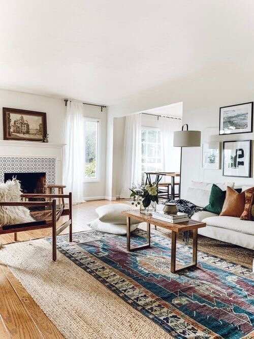 A boho rug layered on top of the jute rug and a wooden coffee table with white sofa
