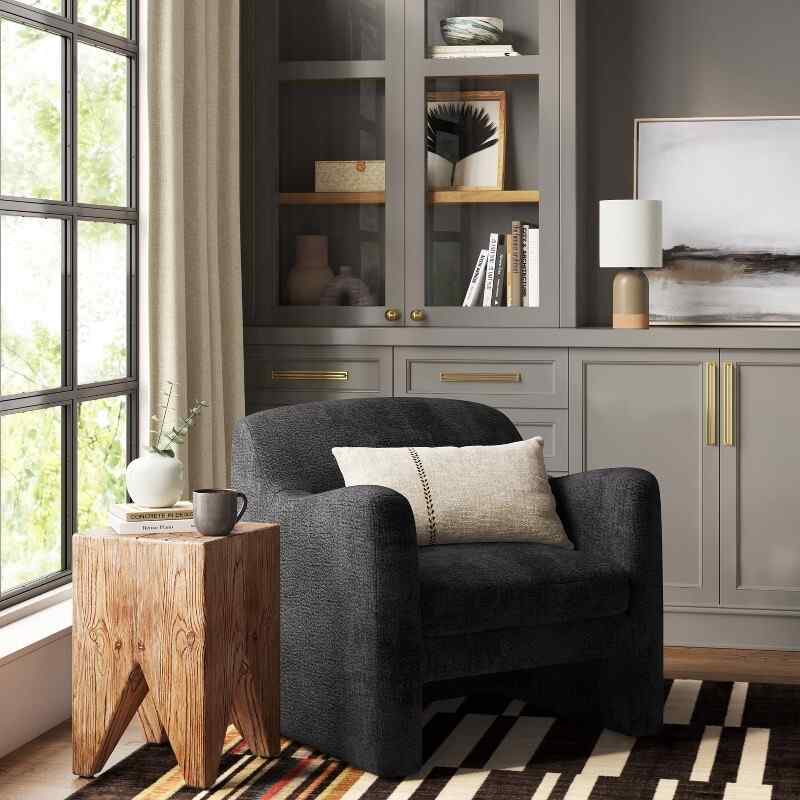 A dark gray armchair against the light gray cabinet in living room