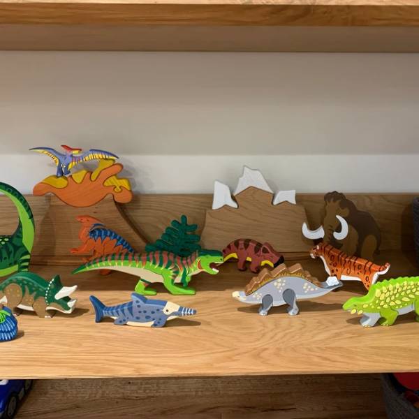 Multi colored dinosaur shapes on a wooden shelves as a display for kids room