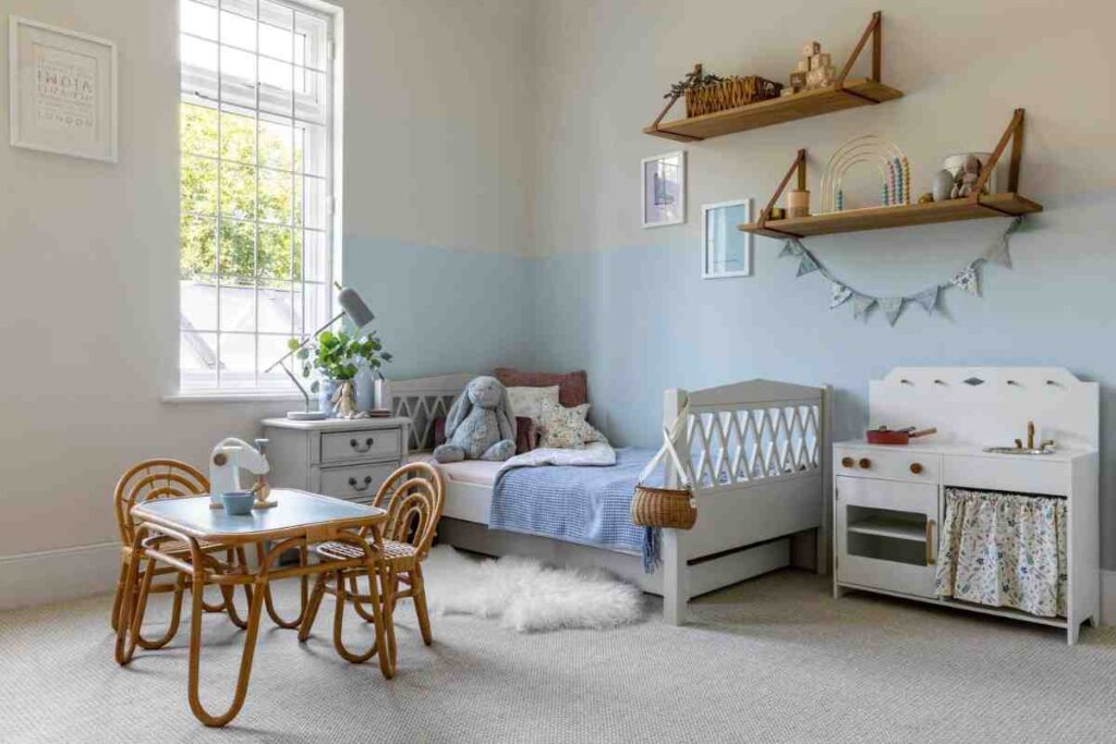 A wooden mini chair and table set with a white bed frame and a mini kitchen set for the toddler room