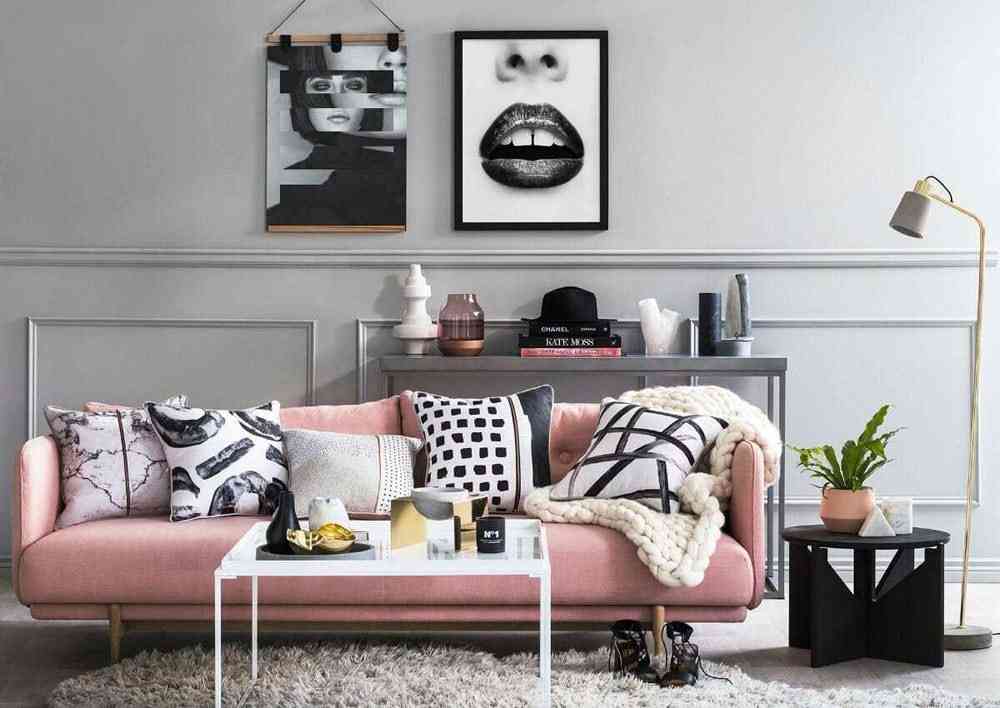 A pink sofa against the gray wall and a black side table