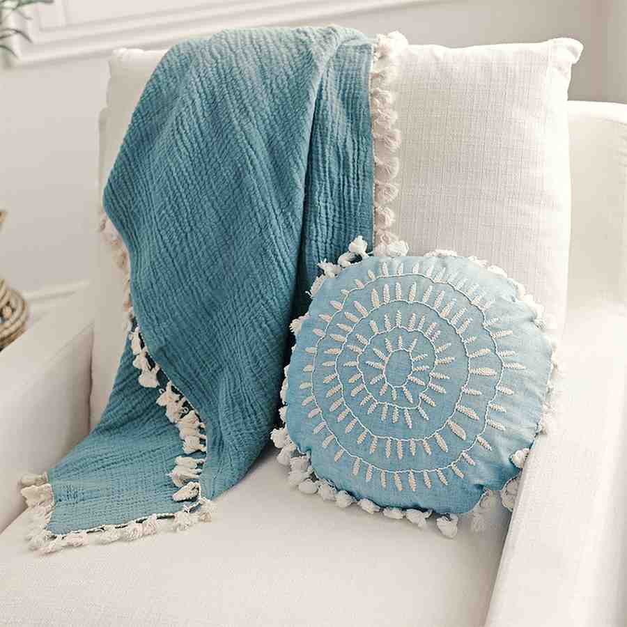 A teal turquoise throw pillow and blanket on a arm chair
