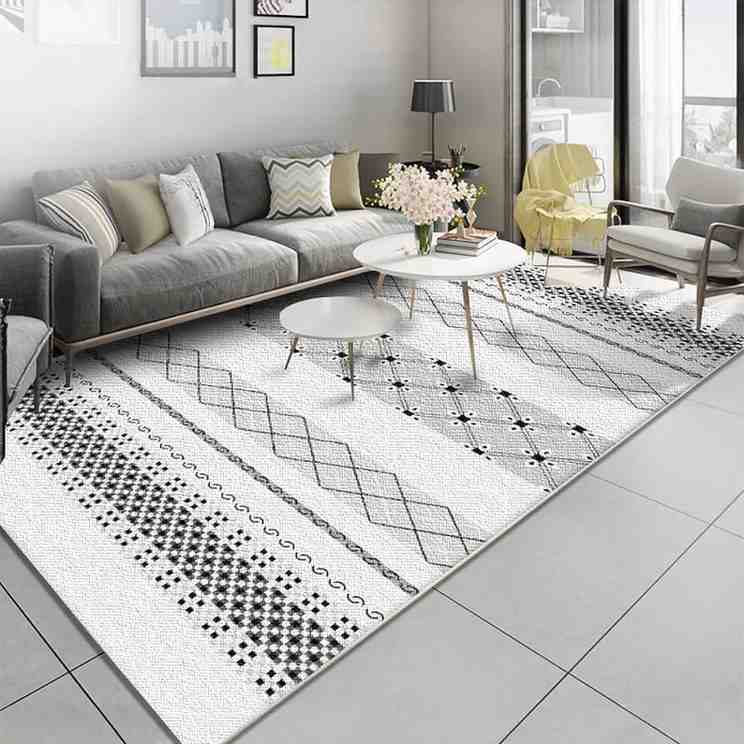 Monochrome style rug with a grey color sofa and a white center table with wooden legs