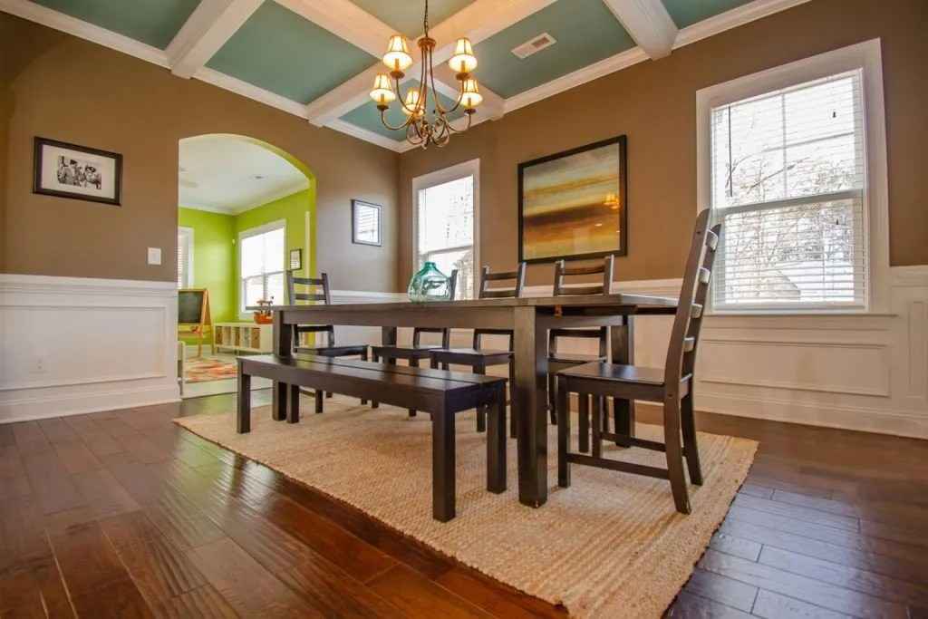 White colored window frames in a dark wood dining room floor with a wooden table and chair set