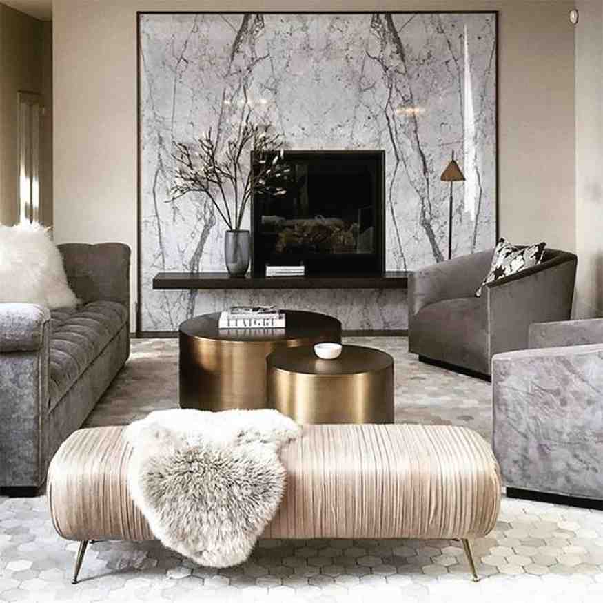 Golden cylindrical table and a satin bench with metal legs and a fur throw blanket on it