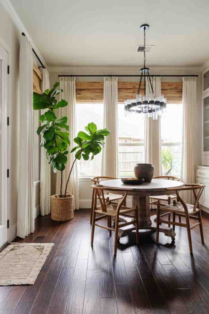 Floor to ceiling sheer curtains paired with a wooden dining table and chair set with a indoor plant