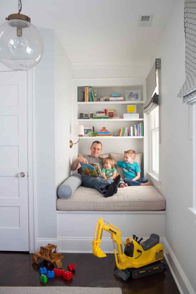 Toys on floor and a reading nook in the corner with white wall and a comfortable seating