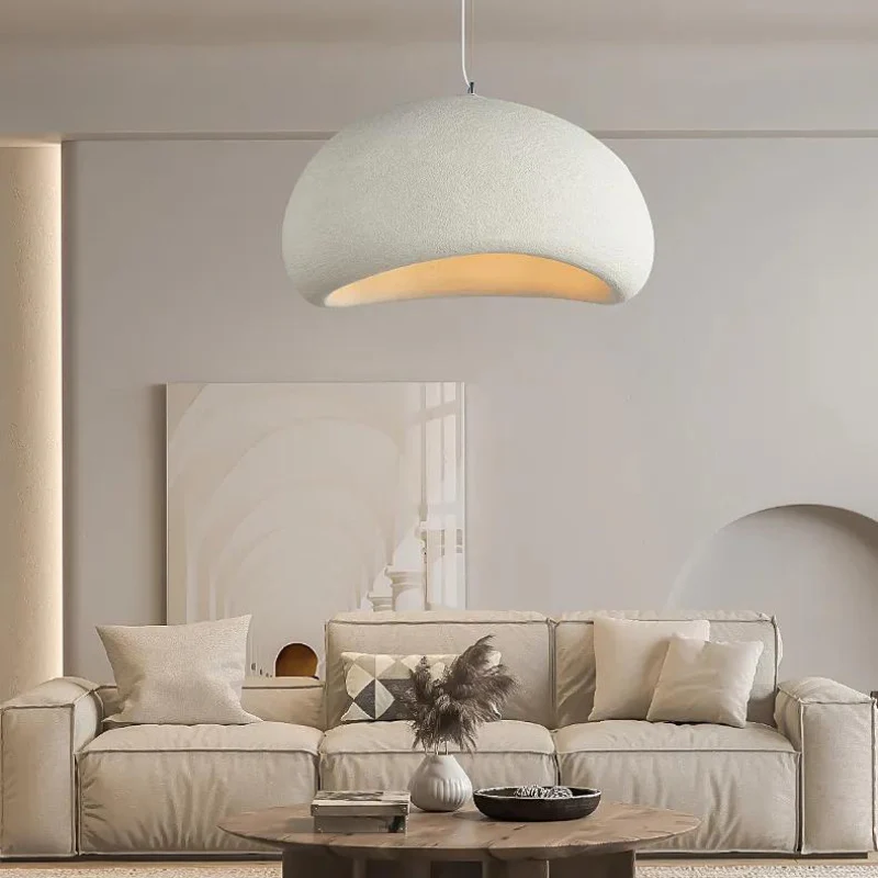 A cream color sofa and white walls and a ceiling pendant lamp