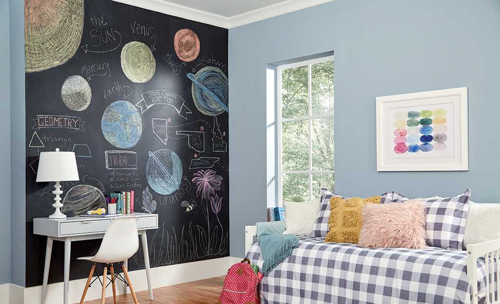 A chalkboard wall with some drawing on it and a white sofa with table