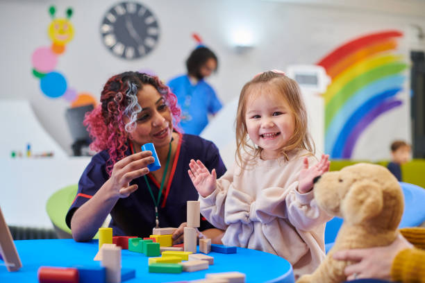 A kid and nurse playing with toys o blue table and a stuff dog toy