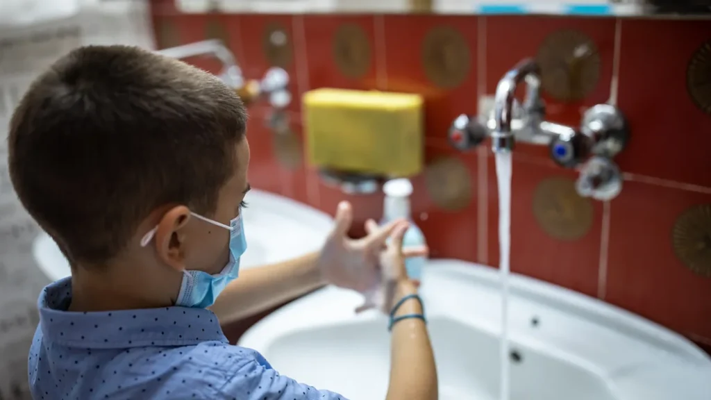 Red tiles on wall and a kid washing hands
