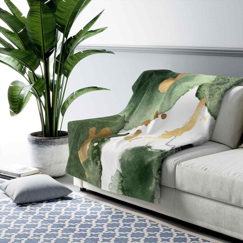 Gray sofa and a green plus golden throw blanket and a plant beside the sofa