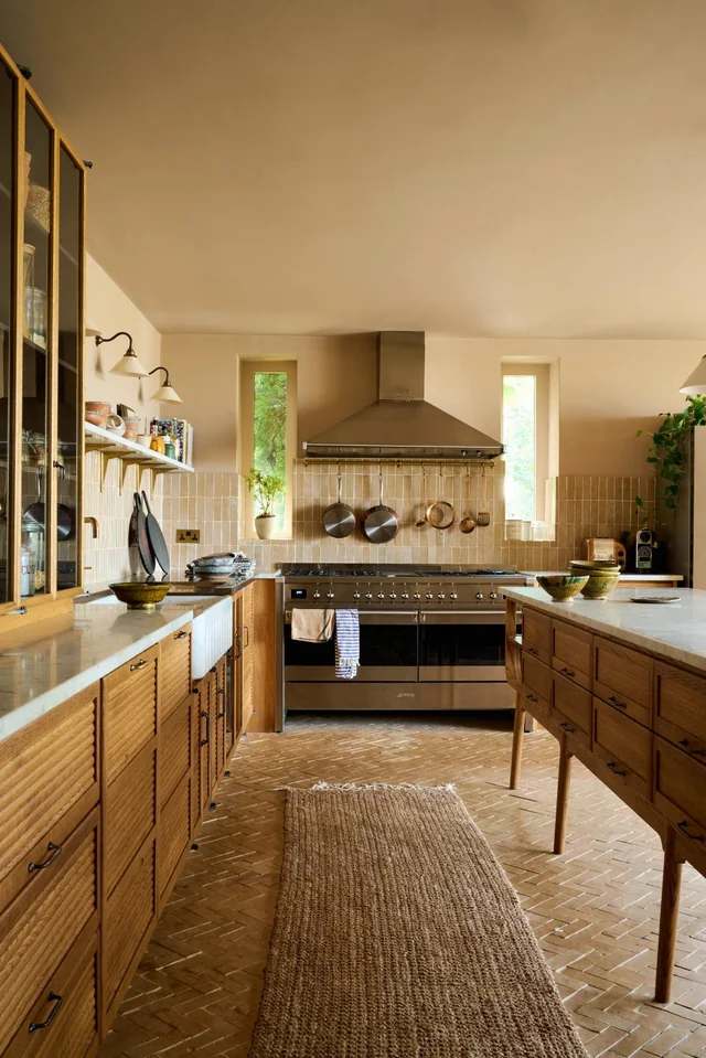 A rattan carpet and wooden table with cabinet and kitchen area with zellige tiles