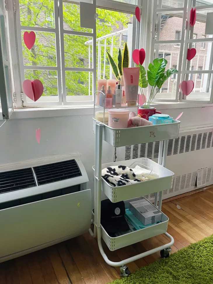 A white rolling trolley with items in it and a white window
