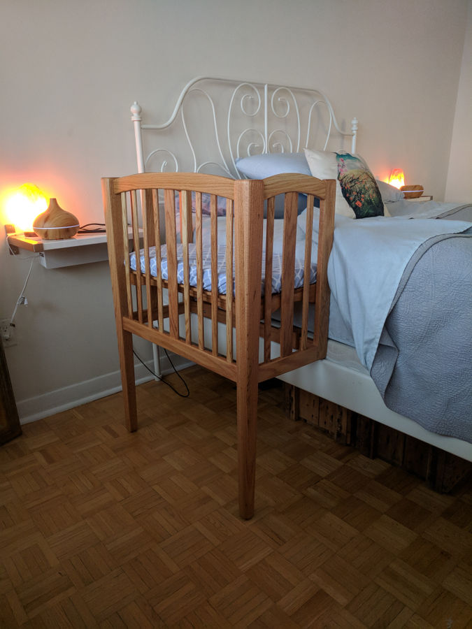 Bed and a wooden sidecar sleeper for baby and white walls