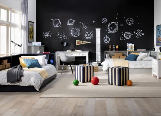 Black chalkboard wall and two bed for the room in white color and two ottoman in stripped style