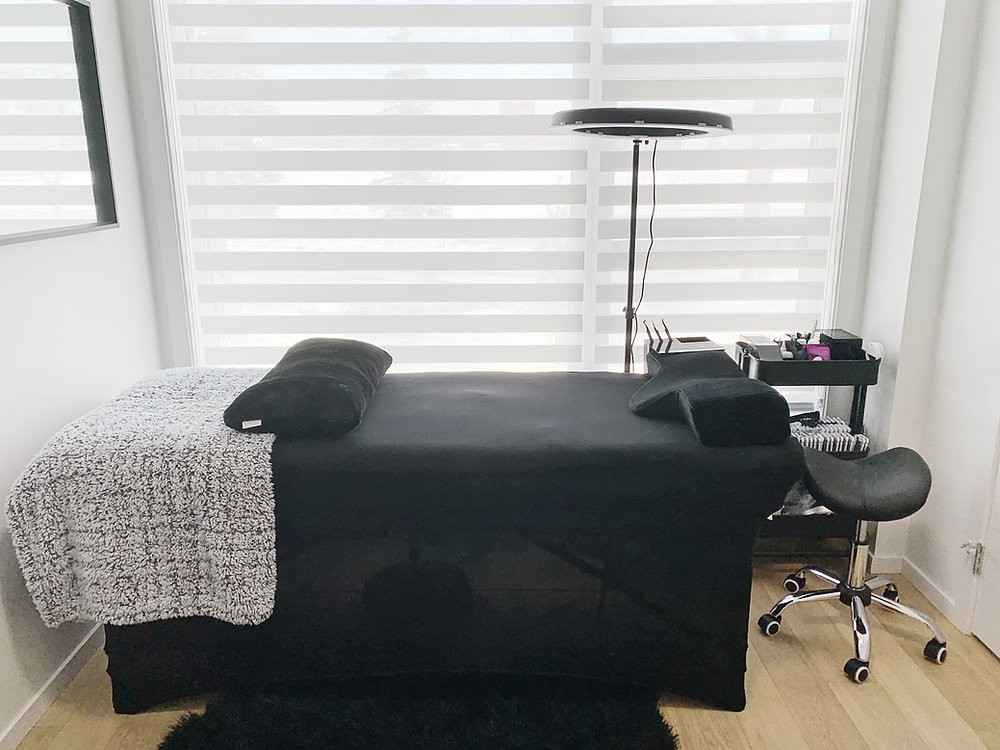 Window with blinds and a black color lash bed with a black stool