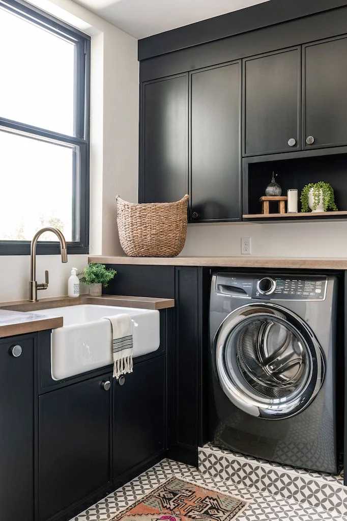 Black cabinet and white sink laundry room with wooden counter top