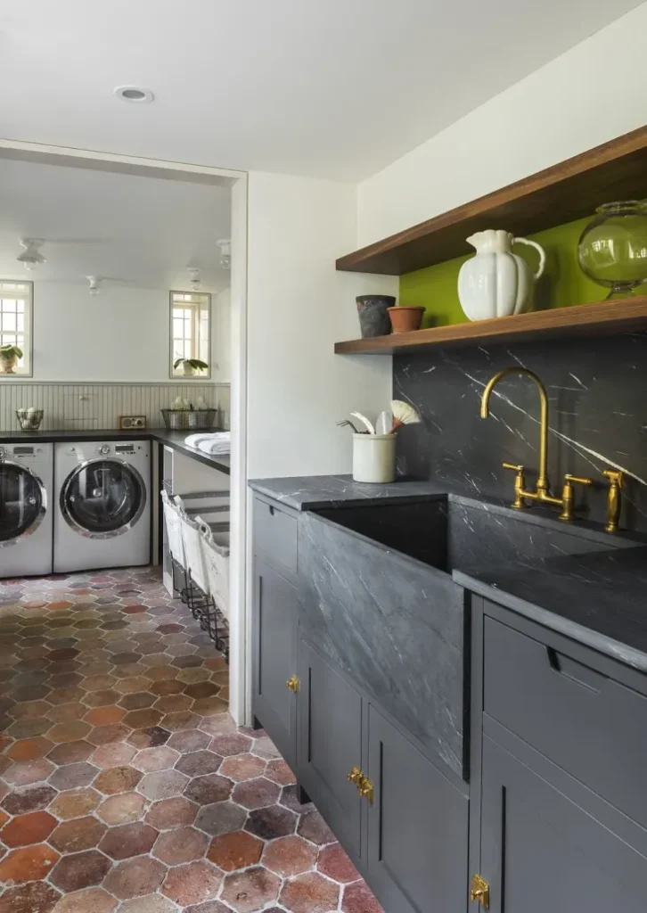 Black marble sink with golden faucet and wooden shelve above it 