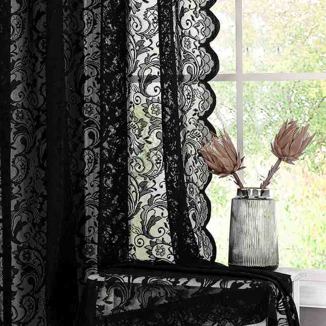 Glass jar and flowers in it and black sheer lace curtains