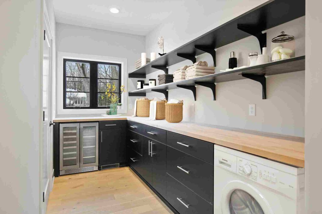 Wooden counter top with black shelves above it and black cabinet 