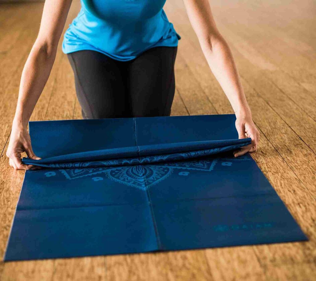Blue color foldable yoga mat and a girl folding it