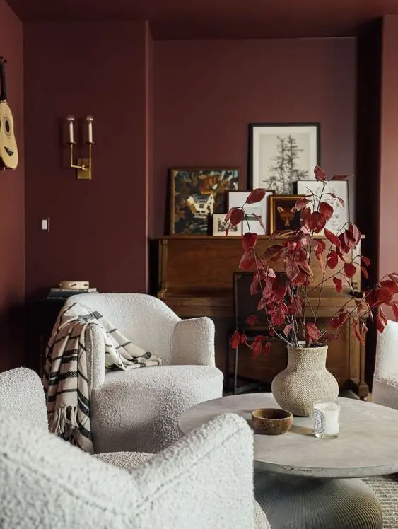 Burgundy color walls and a coffee table with a flower pot and and two chair