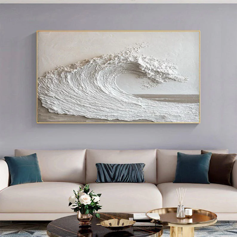 Cream sofa and a ocean wave art frame above it and a round coffee table