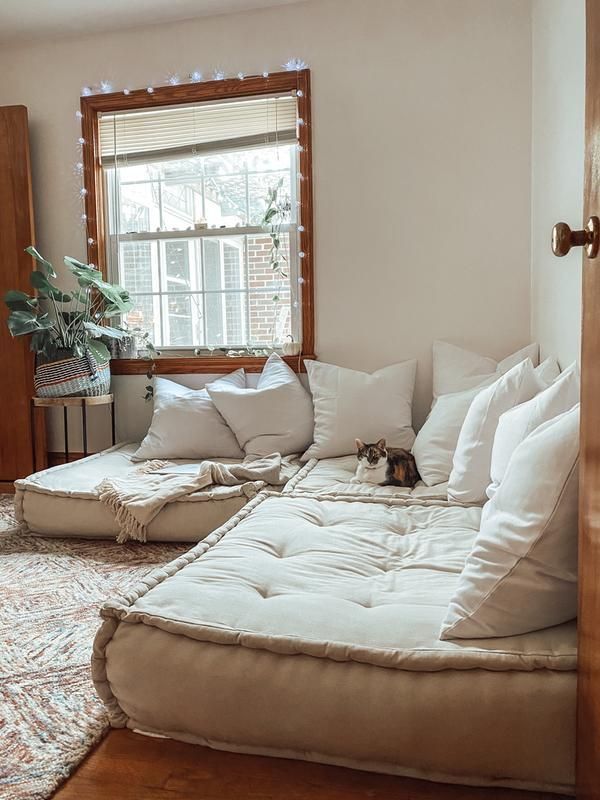 Floor white Couch Cushion and a wooden window with fairy light and a side table