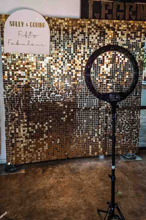 Golden shimmer fringe wall and a ring light for the photo booth area