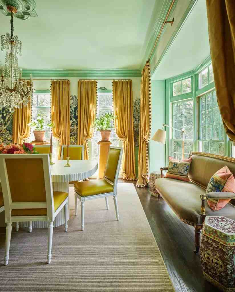 Golden yellow floor to ceiling length curtains and green wall with a seating area